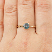 Close-up of hand wearing Nina Ring with 0.98ct light green Montana sapphire set in 14k rose gold band