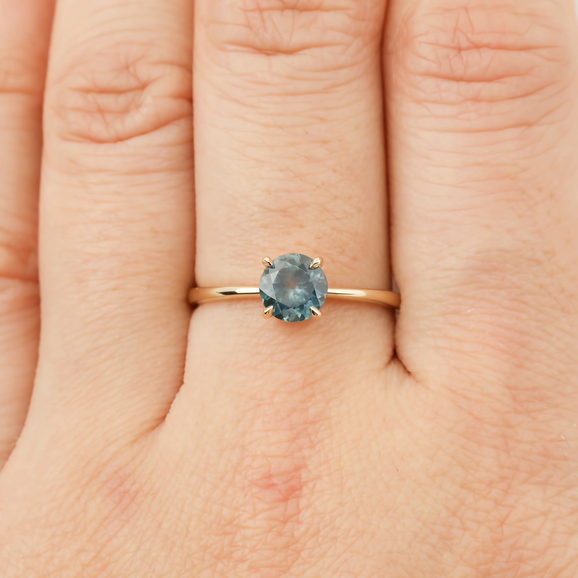 Close-up of hand wearing Nina Ring with 0.98ct light green Montana sapphire set in 14k rose gold band