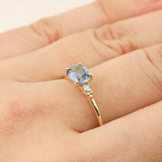 Gold ring with 0.97ct blue sapphire and small white diamonds in a four-prong flower setting on a hand