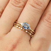 Hand wearing Estel Ring with 0.97ct oval blue sapphire and white diamond accent in 14k recycled gold band