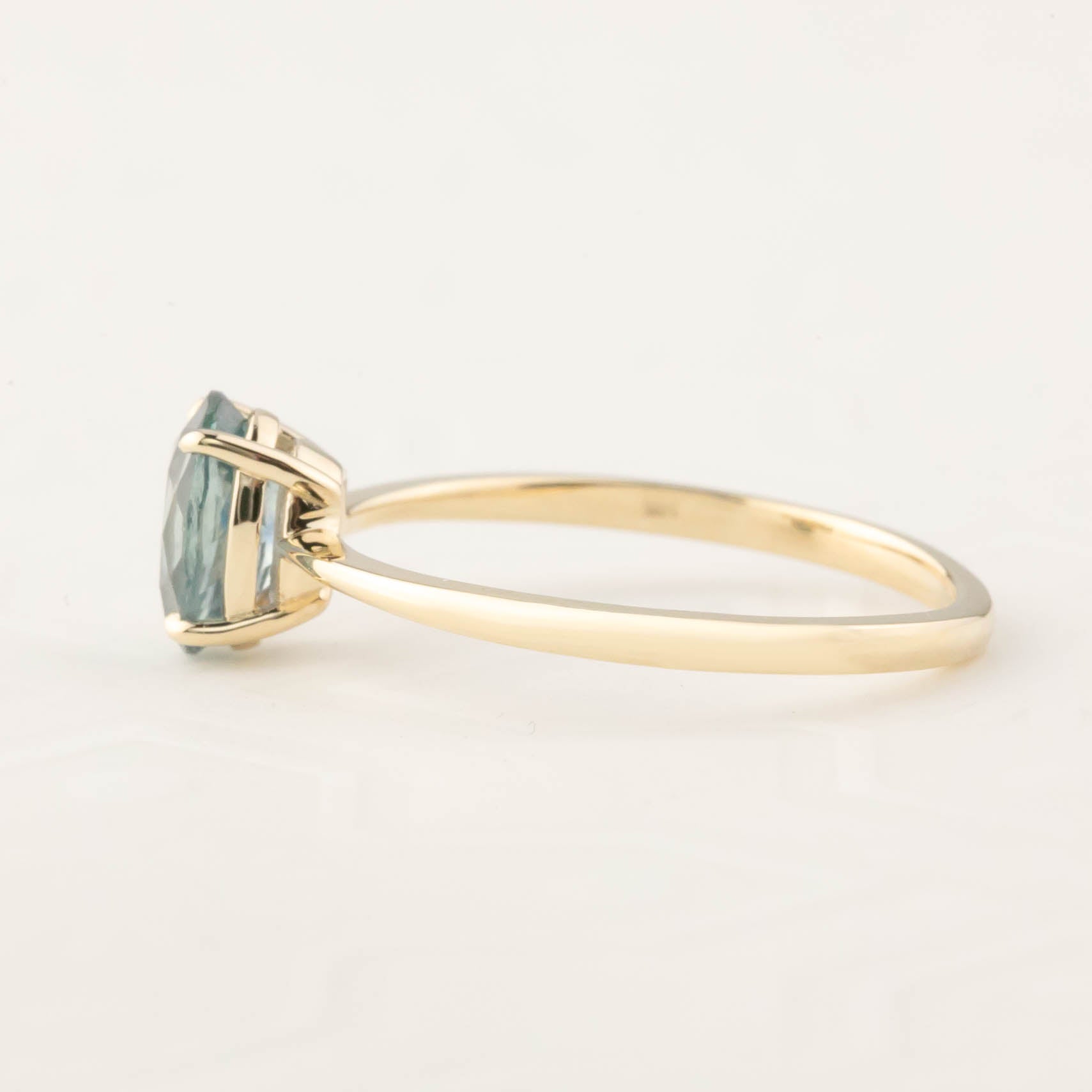 Side view of a Nina Ring featuring a 1.24ct light teal blue Montana Sapphire set in 14k yellow gold band