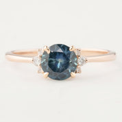 Rose gold ring with a 1.15ct teal blue Montana sapphire and small white diamond accents in a four-prong setting.