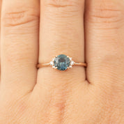Hand wearing Lena Ring with 1.16ct Montana sapphire and small white diamonds set in 14k rose gold band