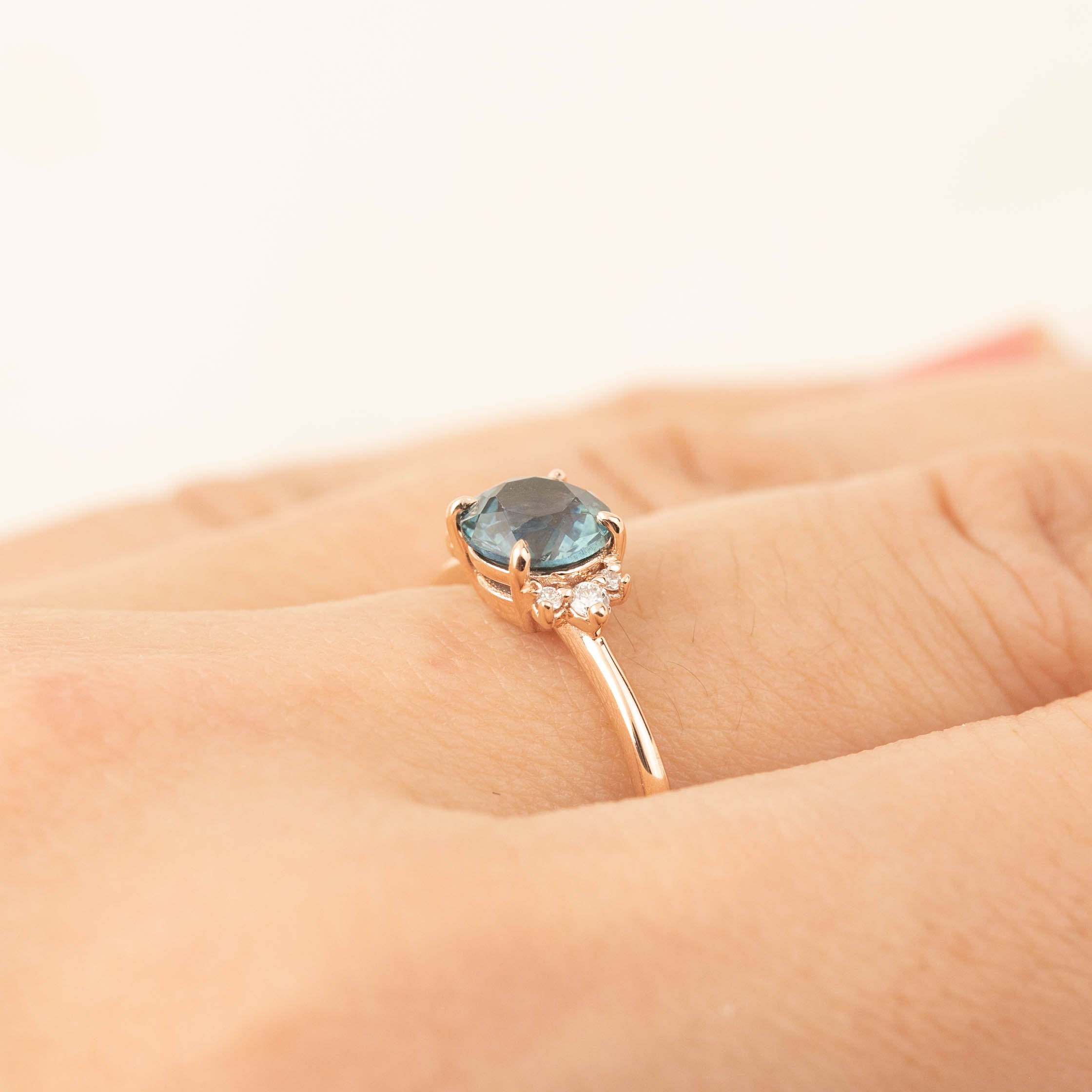 Lena Ring with 1.16ct Montana sapphire and white diamonds set in recycled 14k rose gold on a hand.