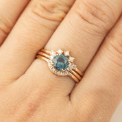 Close-up of Lena Ring with 1.15ct teal blue Montana sapphire and diamonds set in 14k rose gold on finger.