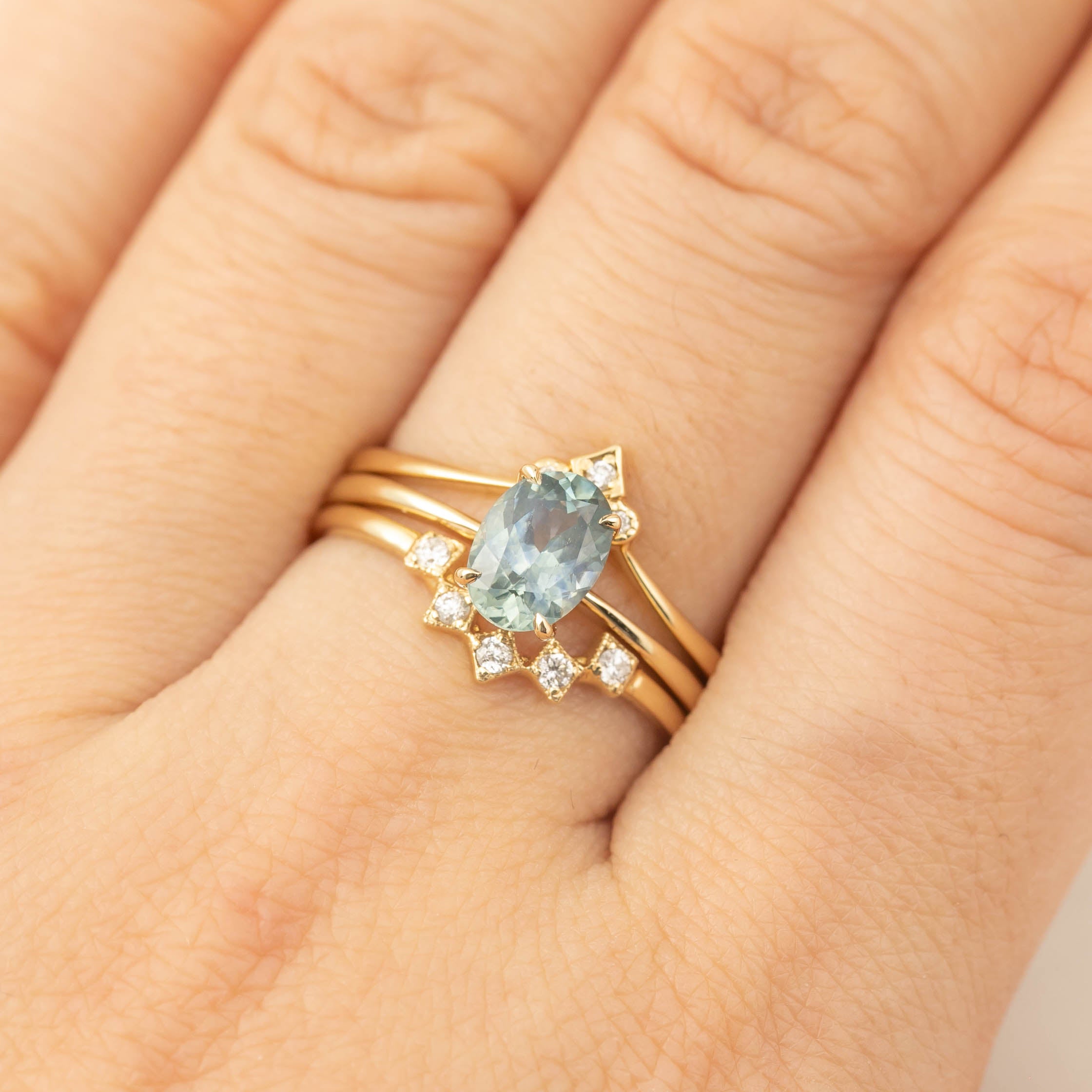 Close-up of Nina Ring with 1.24ct light teal blue Montana sapphire set in 14k yellow gold on finger