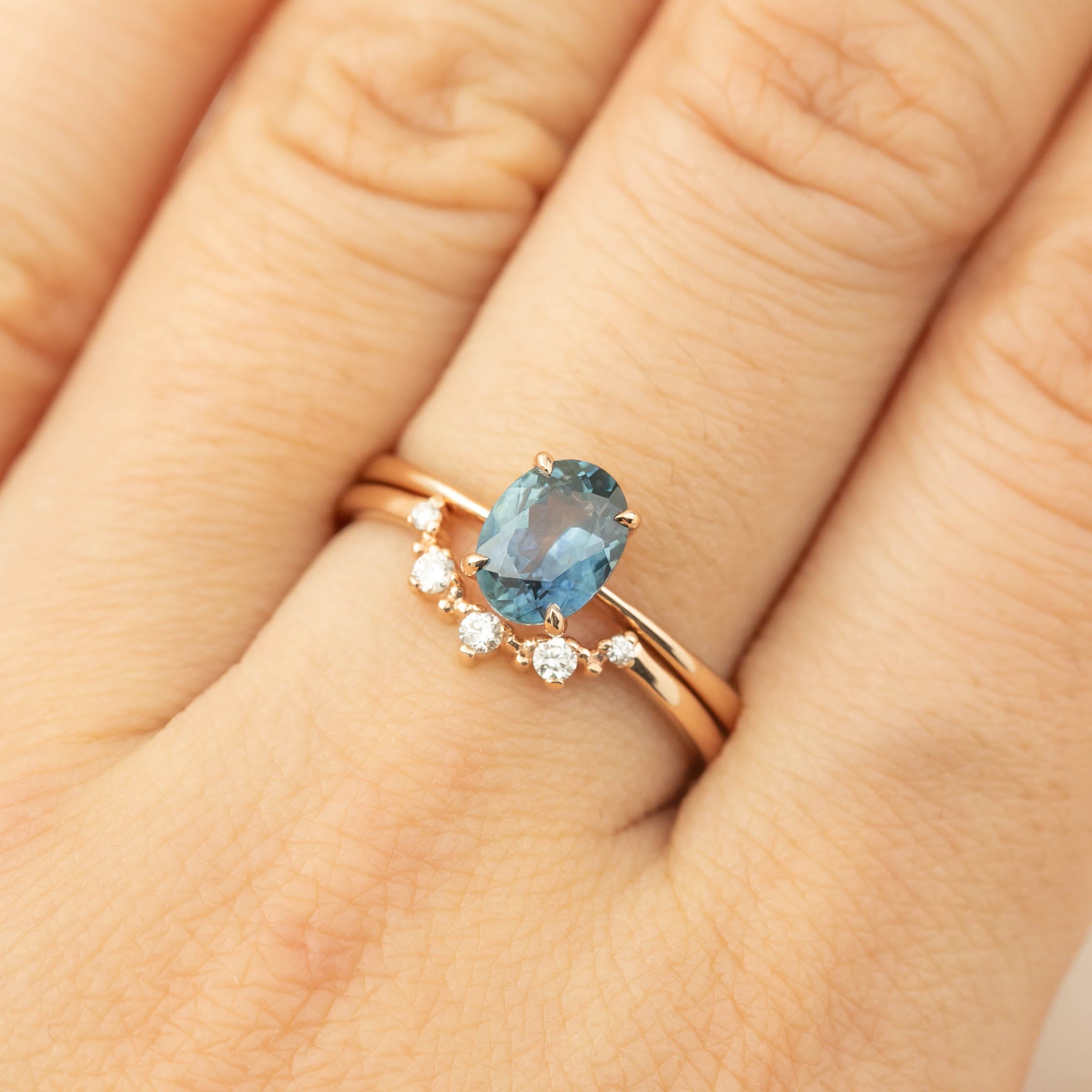Rose gold ring featuring a 1.22ct teal blue Montana sapphire with small accent diamonds on finger size 7