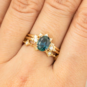 Close-up of a hand wearing a one-of-a-kind 1.56ct teal blue Montana sapphire ring with white diamonds in 14k gold