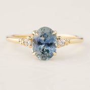 Gold ring featuring a 1.62ct teal Montana sapphire and two small white diamond accents in a four-prong setting.