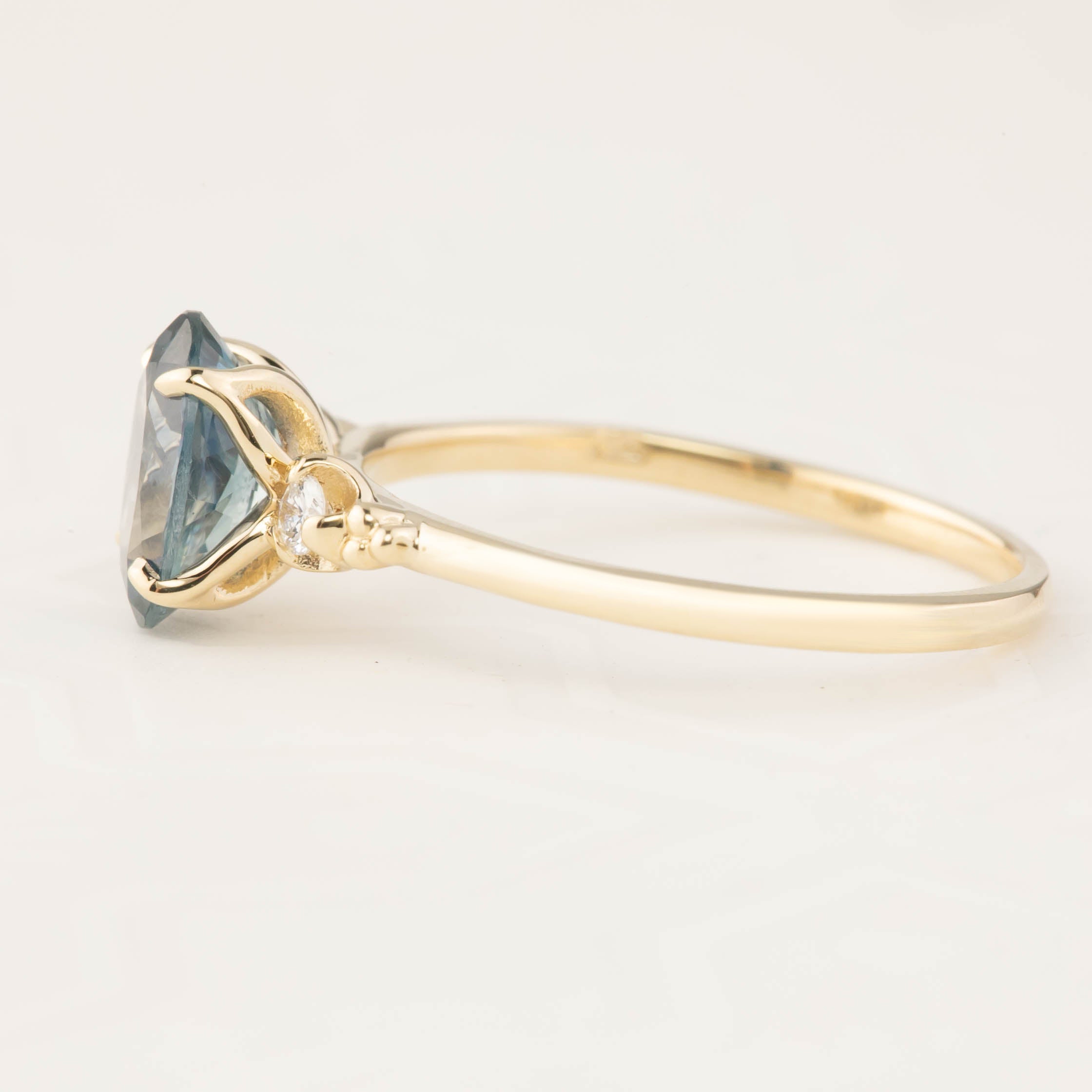 14k gold ring with 1.62ct teal Montana sapphire in four-prong flower setting and small diamond accents