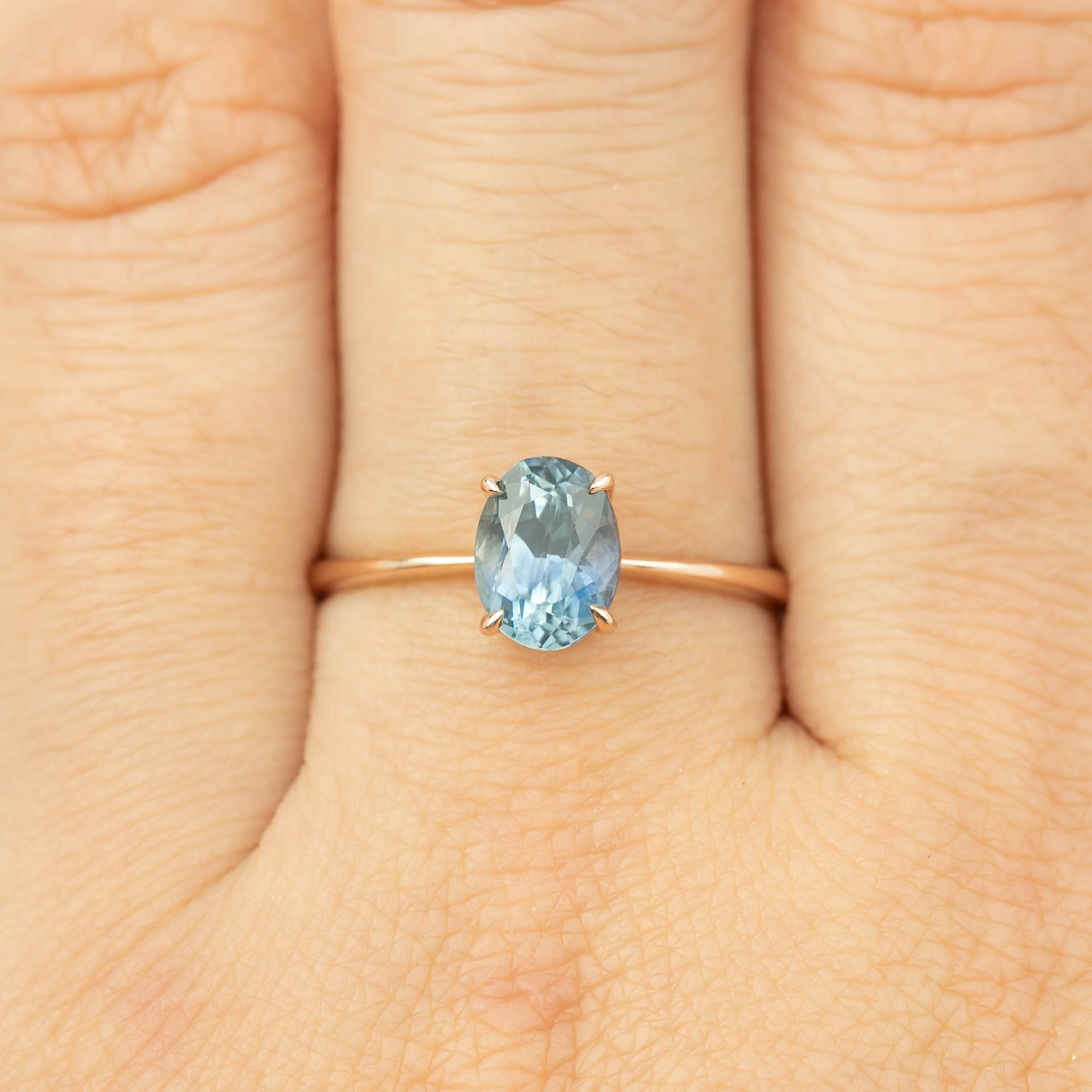 Close-up of a one-of-a-kind 1.4ct blue Montana sapphire ring set in 14k rose gold on a finger