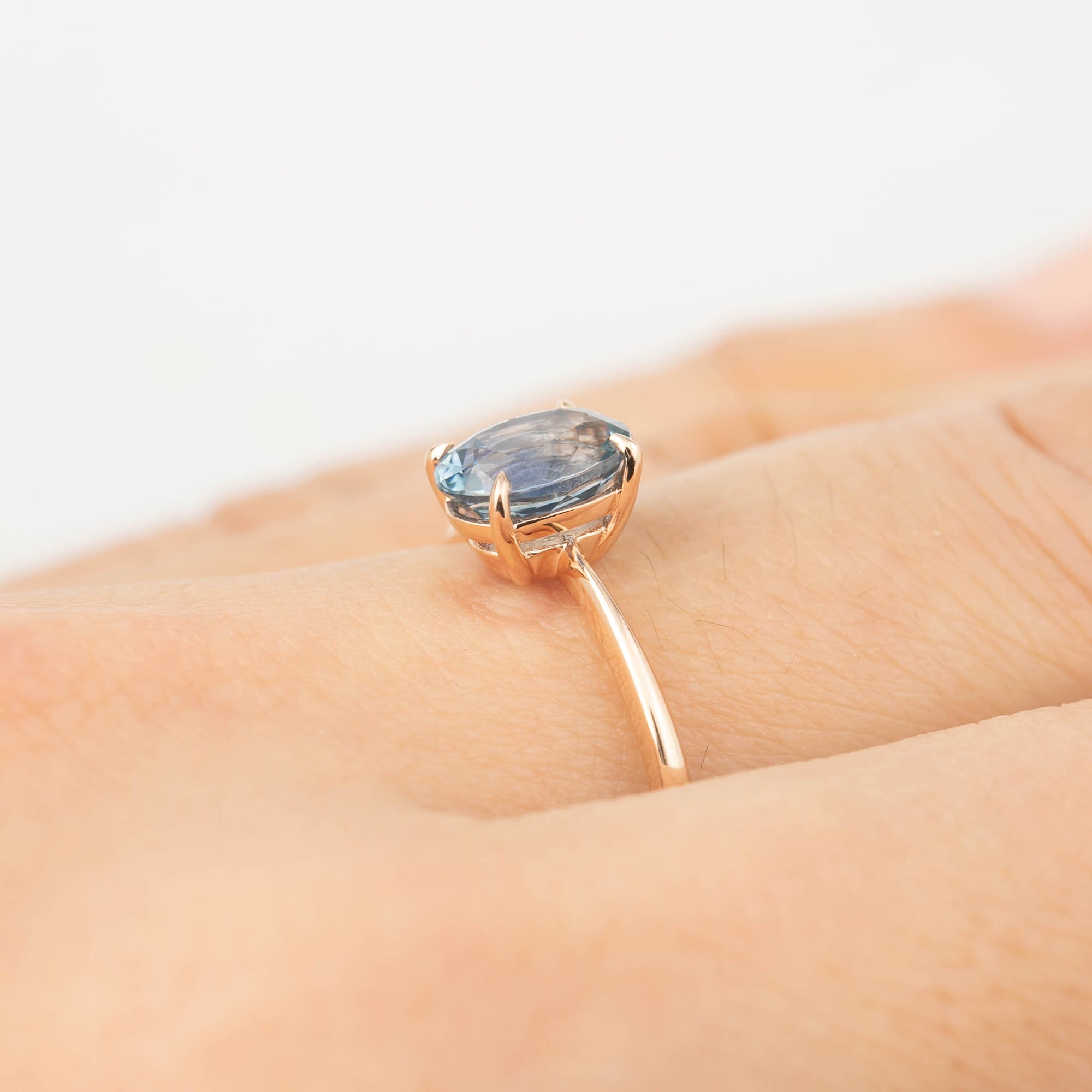 Close-up of a 1.4ct blue Montana sapphire ring set in recycled 14k rose gold on a finger
