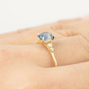 Close-up of Estel Ring featuring 1.25ct blue sapphire and diamond accents set in 14k recycled gold on a hand.