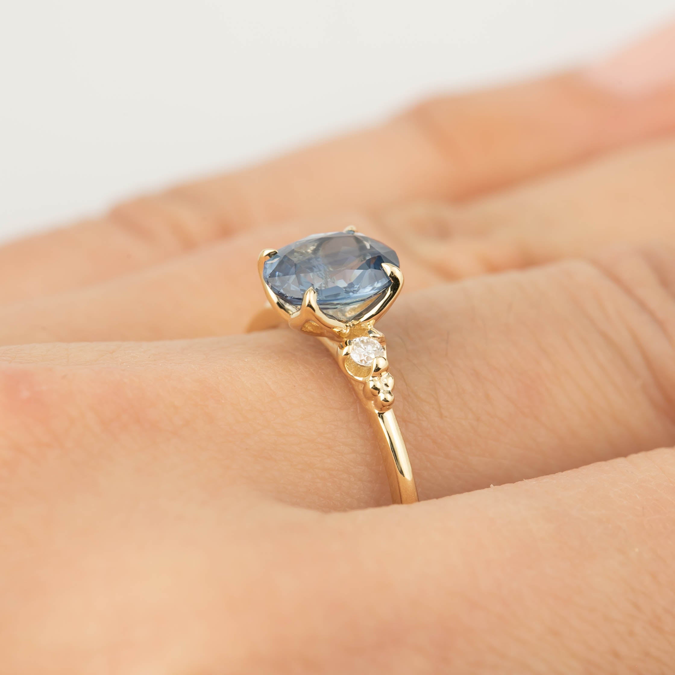 Close-up of a 14k gold Estel ring featuring a 1.53ct blue sapphire and diamond accents on a finger.