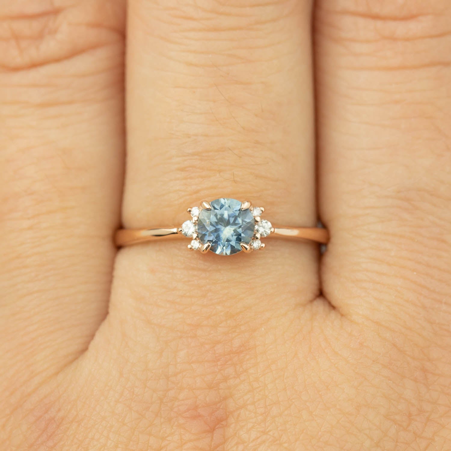 Delicate 14k rose gold ring with 0.72ct blue Montana sapphire and small brilliant cut diamonds on finger size 7.