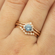 Close-up of a 0.72ct blue Montana sapphire ring set in 14k rose gold with small diamonds on a finger.