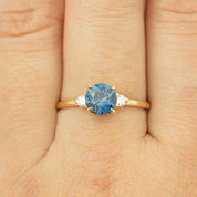 Gold ring with 1.46ct Montana sapphire center and two side diamonds worn on finger, resizable size 4-8.5