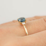 Close-up of Emilie Ring with 1.46ct Montana sapphire and diamond accent set in recycled 14k gold band on finger