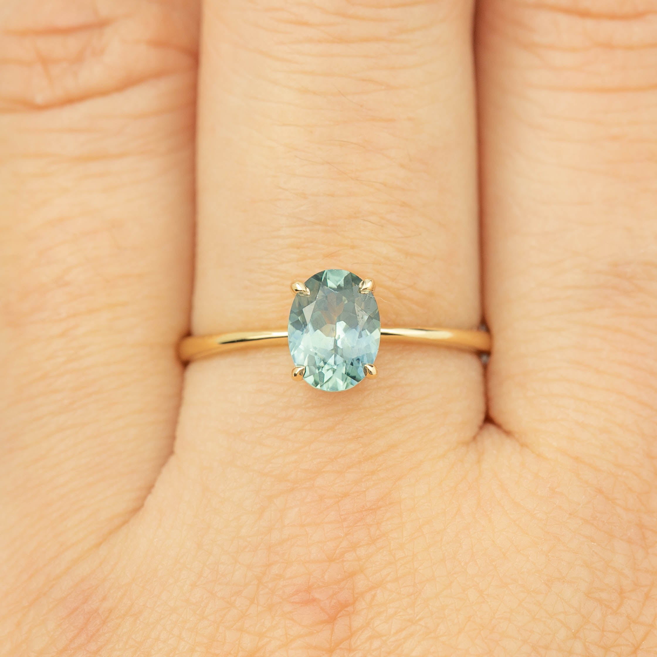 Close-up of Nina Ring featuring a 1.26ct Montana sapphire set in recycled 14k yellow gold on a hand.