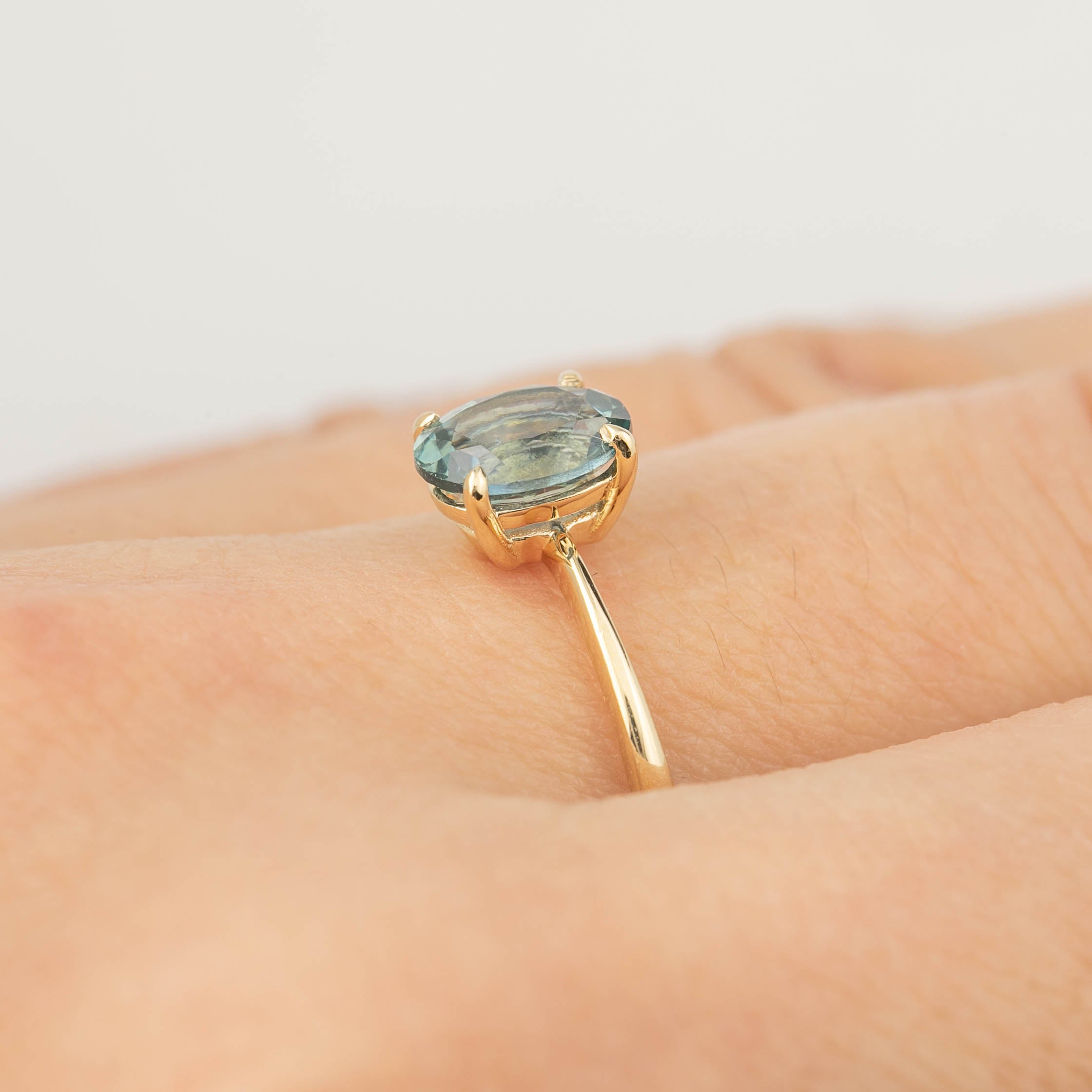 Close-up of a gold ring with a 1.26ct GIA certified Montana sapphire set in four prongs on a hand.