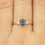 Close-up of Estel Ring featuring 1.24ct blue sapphire and diamond accents set in 14k rose gold band on finger