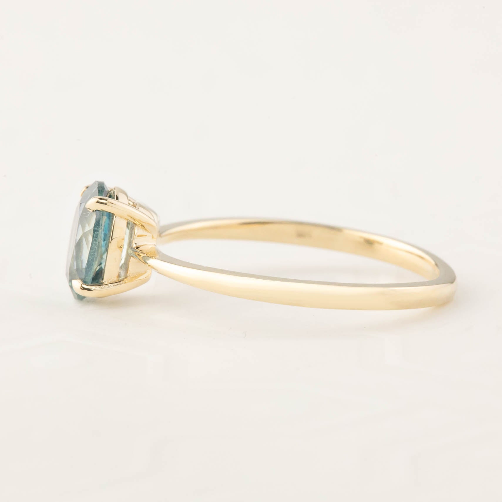 Side view of Nina Ring featuring 1.26ct Montana sapphire in 14k yellow gold four-prong basket setting