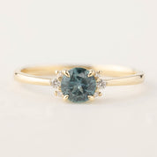 14k gold ring with 0.66ct teal Montana sapphire and small brilliant cut diamonds in a four prong setting