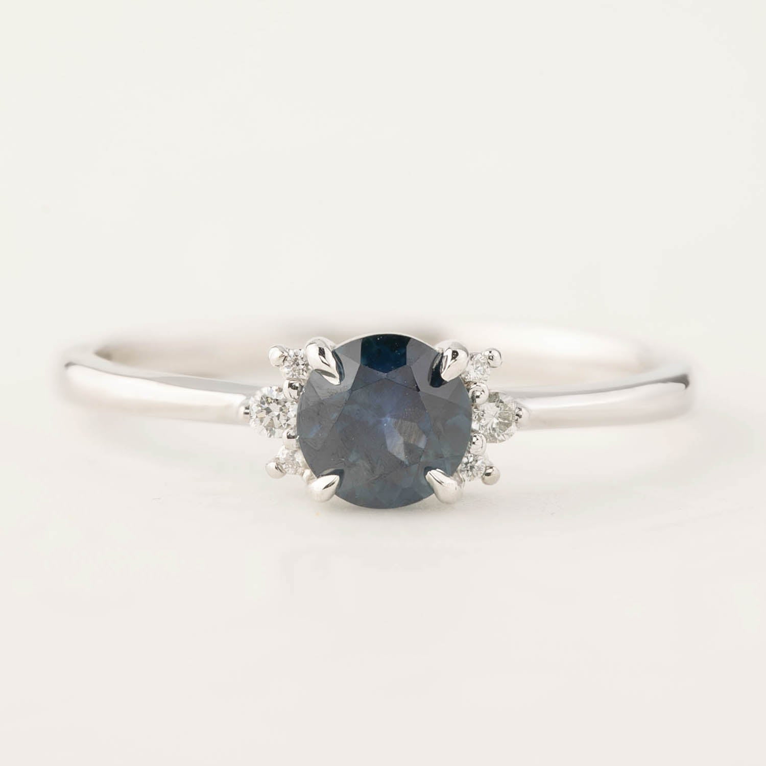 Close-up of Lena Ring with 0.65ct blue Montana sapphire and small diamonds set in 14k white gold band
