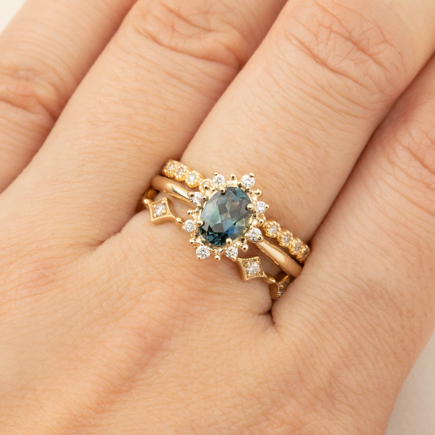 Close-up of a hand wearing a gold eternity ring with natural white diamonds and a central blue gemstone.
