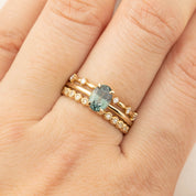 Close-up of hand wearing Sara Ring with 1.36ct green peacock sapphire and 14k yellow gold flower setting band