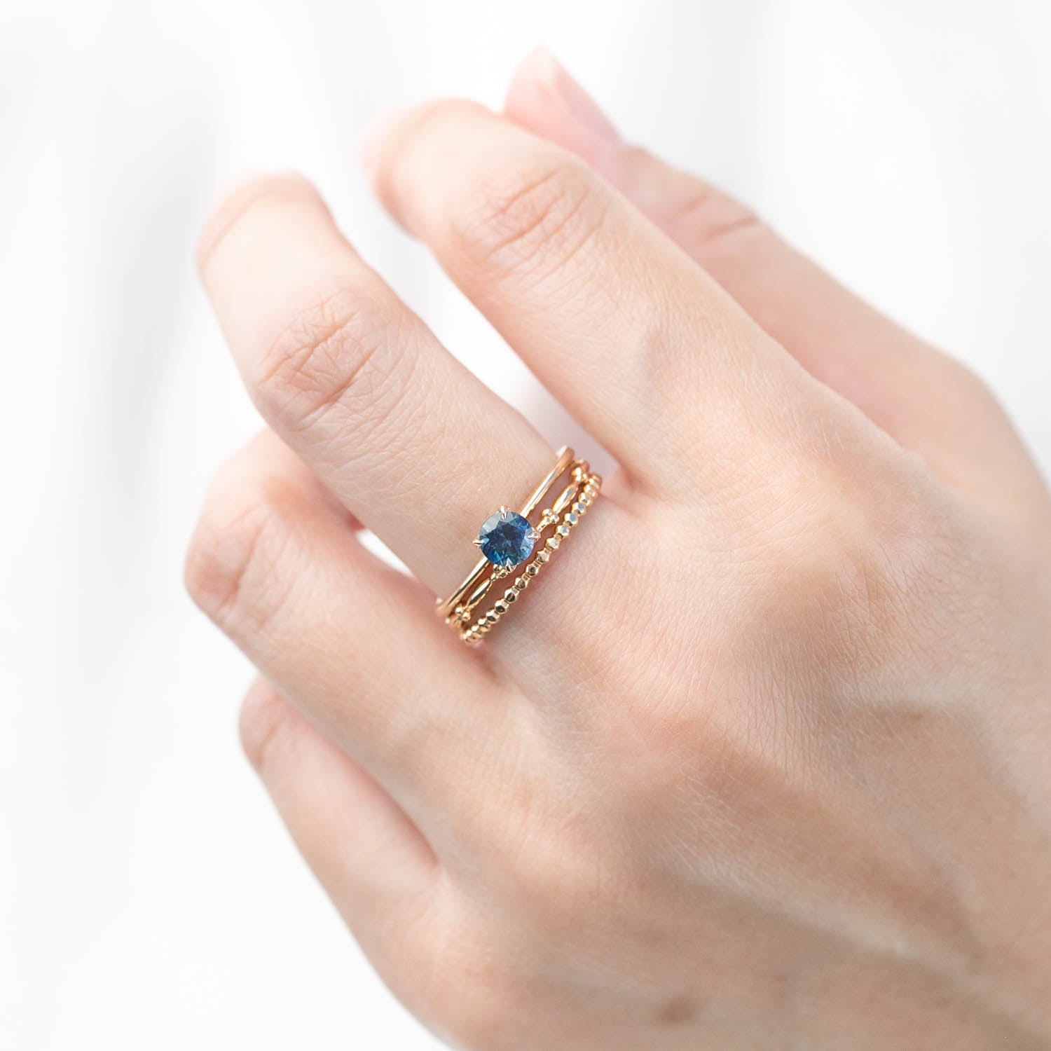 Solid 14k yellow gold ring with 0.66ct teal Montana sapphire and signature flower setting on finger