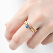 Hand wearing Sara Ring with 0.66ct teal Montana sapphire set in 14k yellow gold tapered band