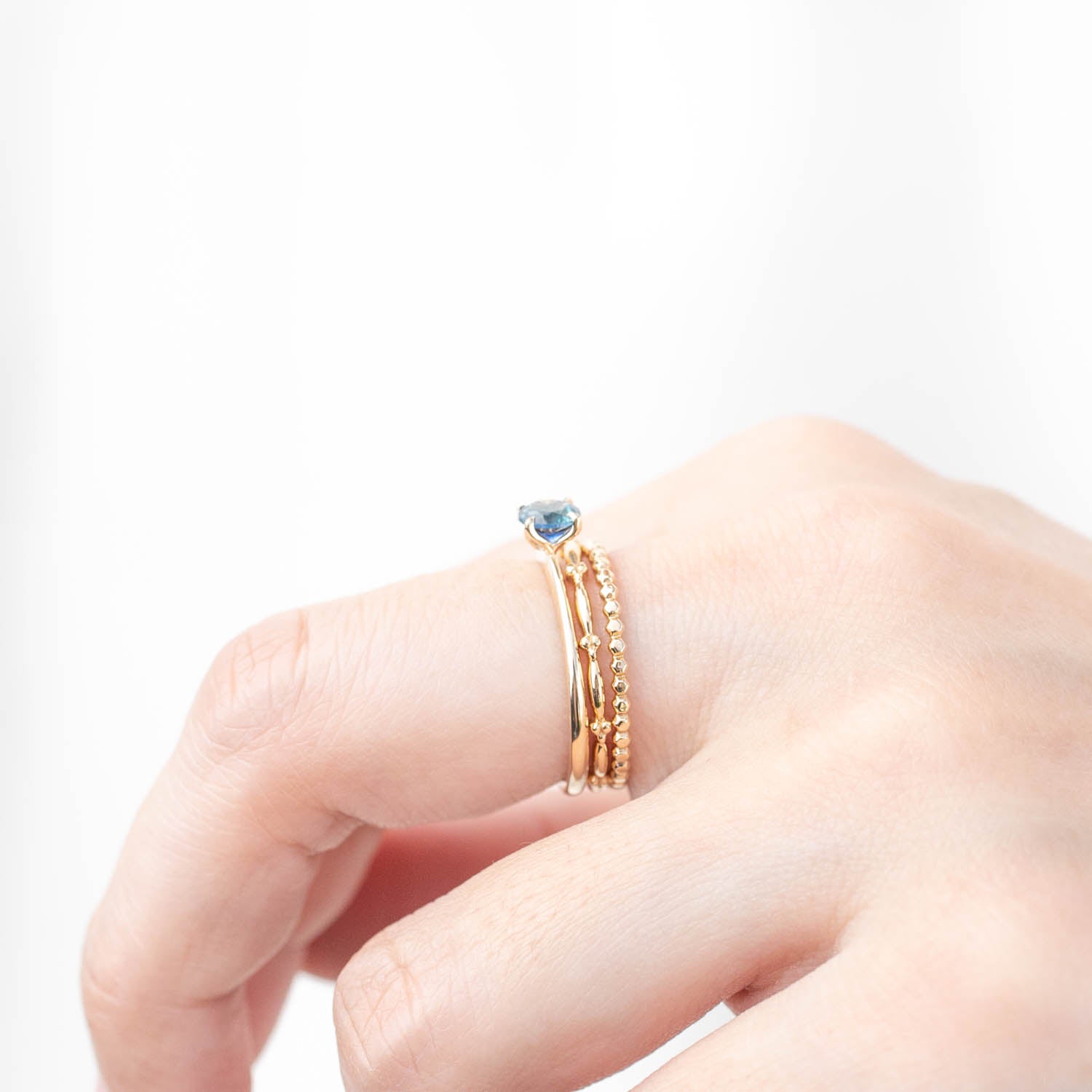 Hand wearing Sara Ring with 0.66ct teal Montana sapphire set in solid 14k recycled yellow gold band