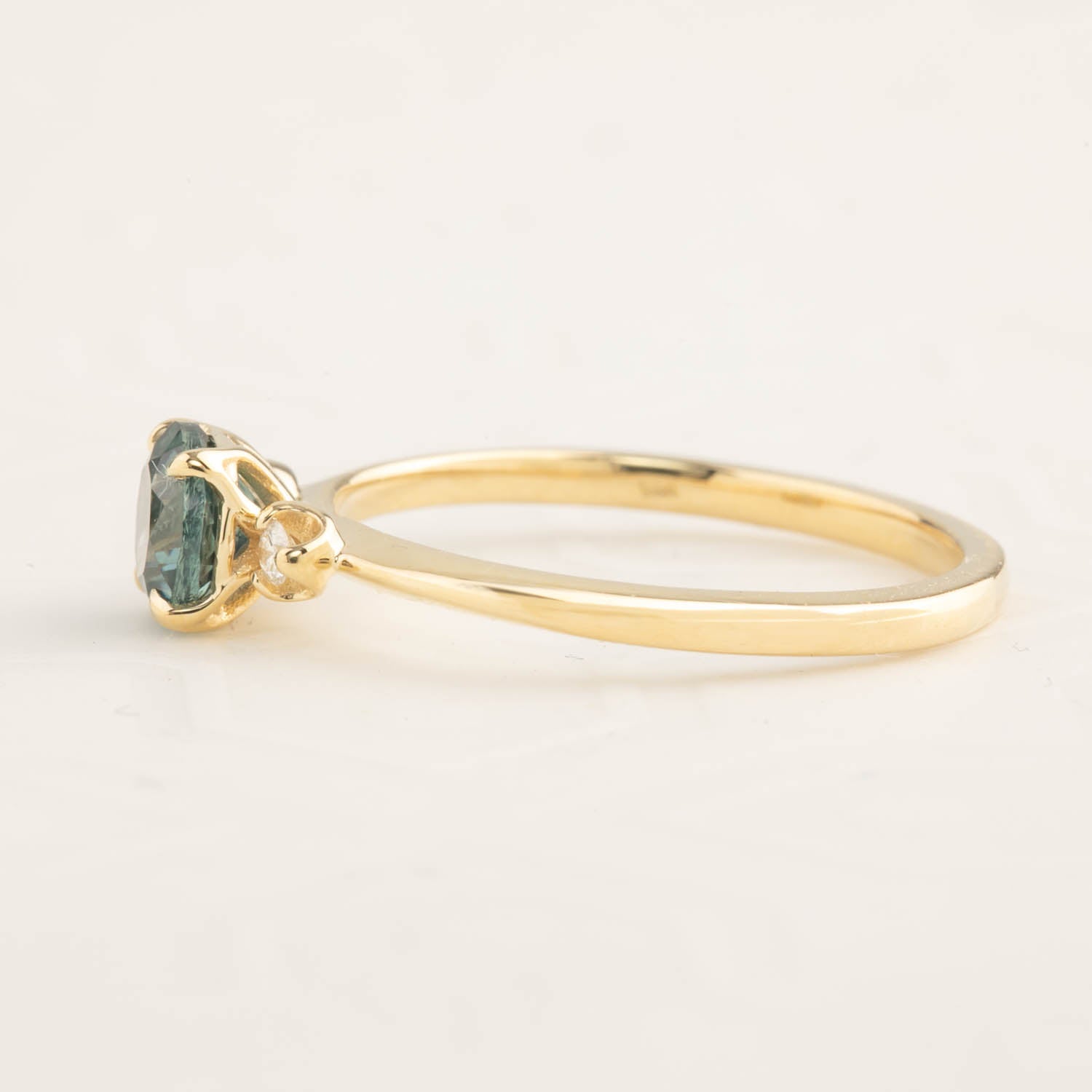 Delicate gold ring with a 0.89ct teal blue Montana sapphire in an elevated setting with a tapered band
