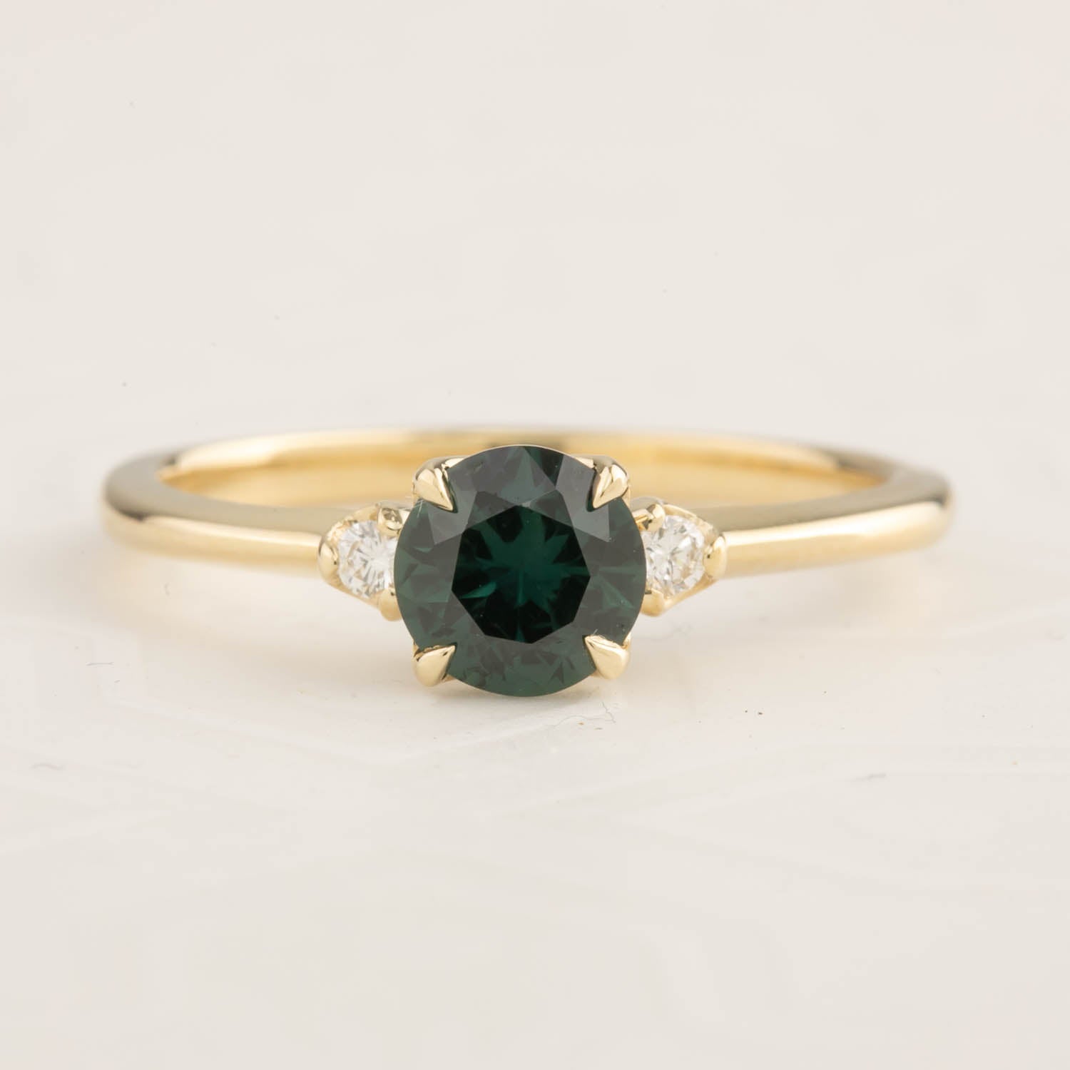 14k yellow gold ring featuring a 0.85ct Queensland peacock sapphire with two white accent diamonds in a four-prong setting