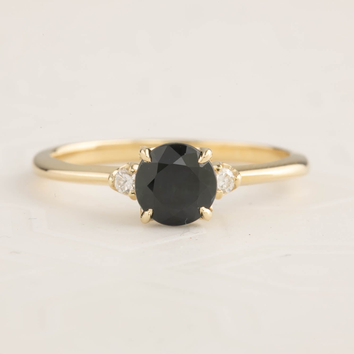 14k yellow gold ring with 1ct dark peacock sapphire and side white diamonds in a delicate tapered band