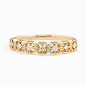 A gold band ring with multiple square-shaped diamond settings, featuring milgrain detailing.