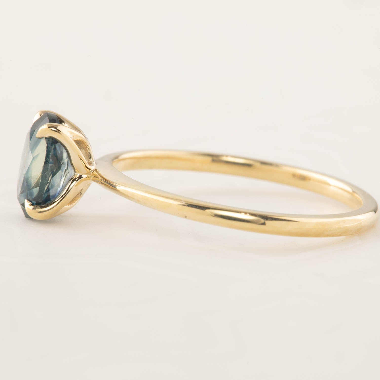 Side view of Sara Ring featuring 1.32ct blue Montana sapphire set in 14k yellow gold with signature flower setting
