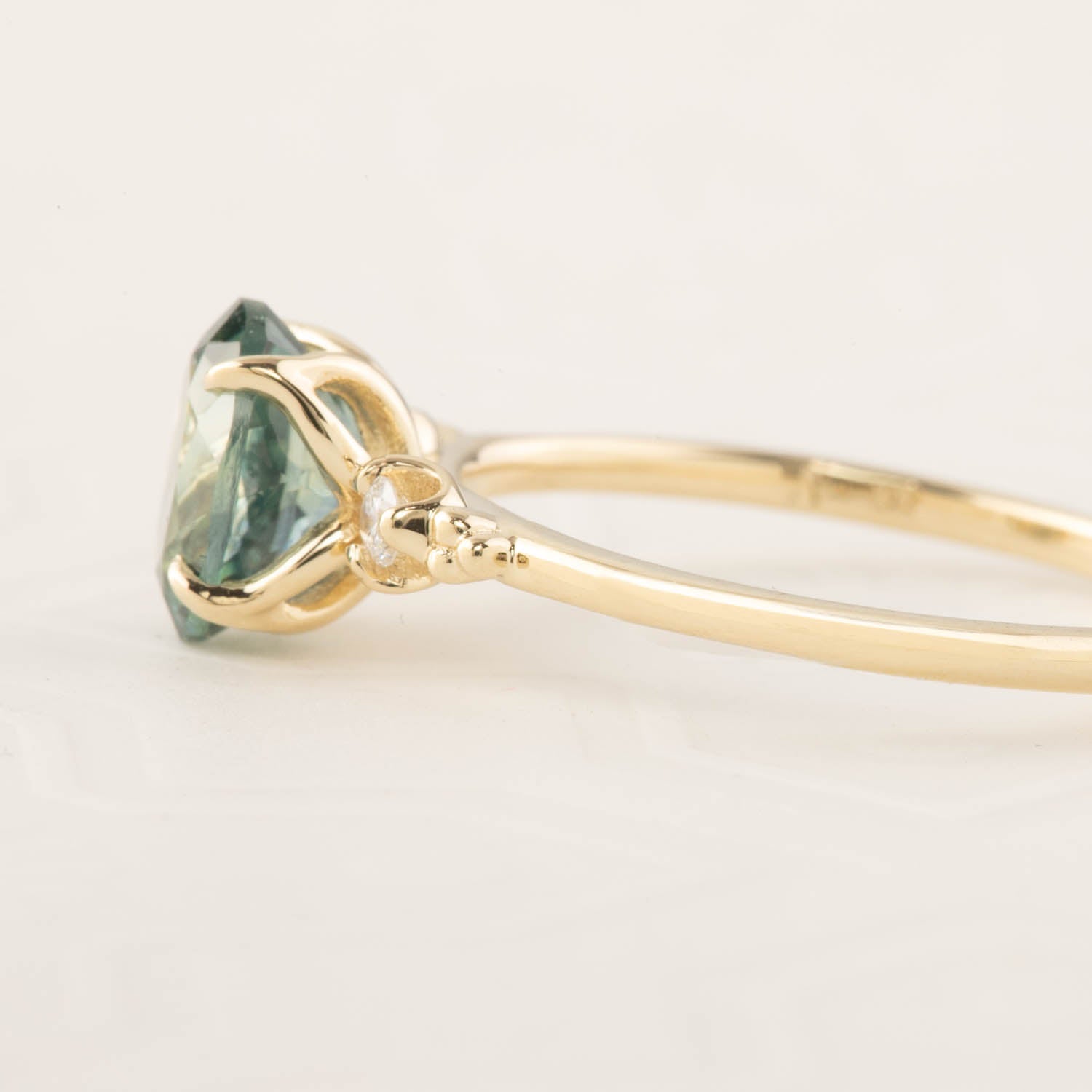 Close-up of a recycled 14k yellow gold ring with a 1.78ct light blue-green Montana sapphire in a four-prong setting
