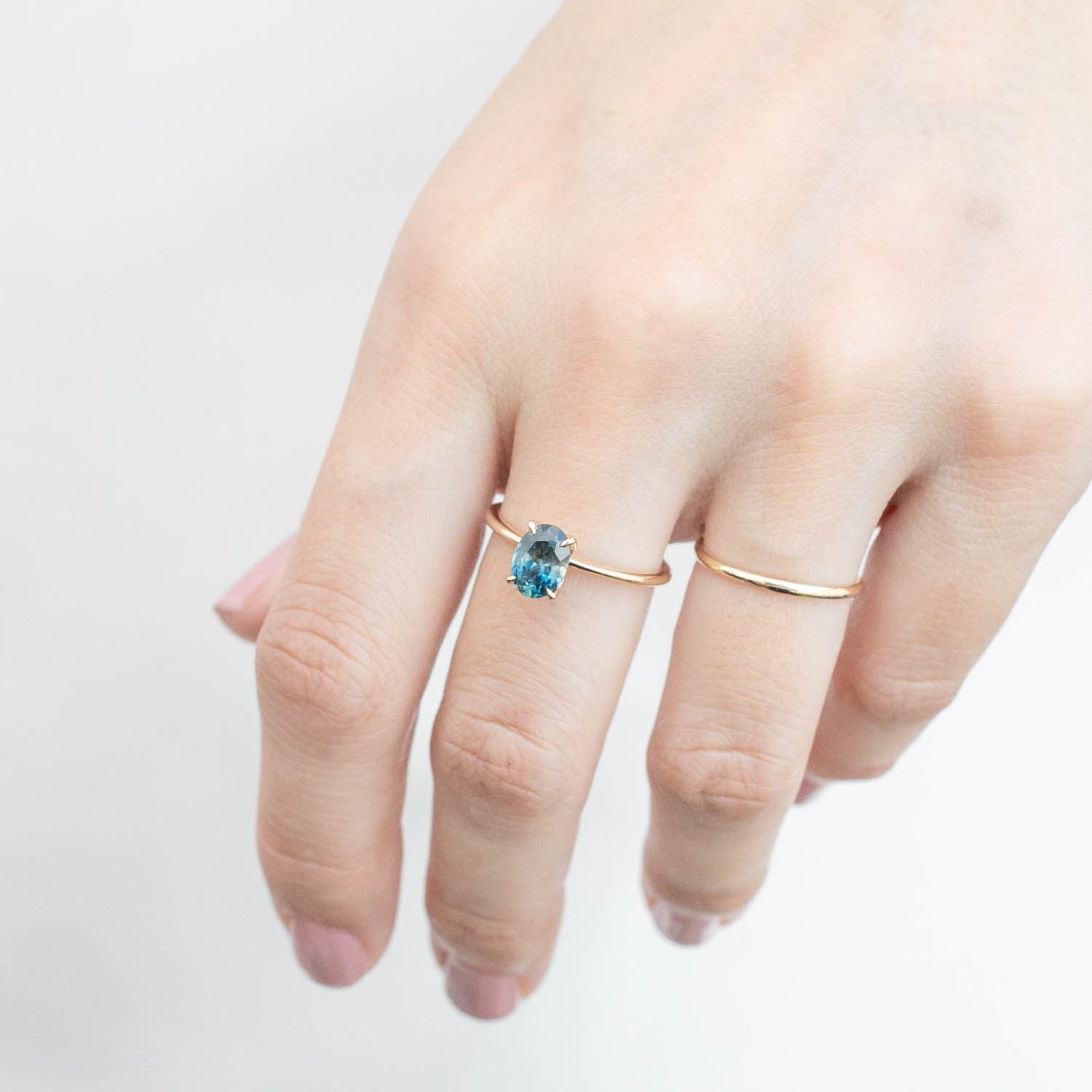 Hand wearing Sara Ring with 1.32ct blue Montana sapphire set in 14k yellow gold flower setting ring
