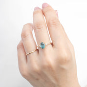 Hand wearing one of a kind 14k yellow gold ring with 1.78ct light blue-green Montana sapphire and accent diamonds