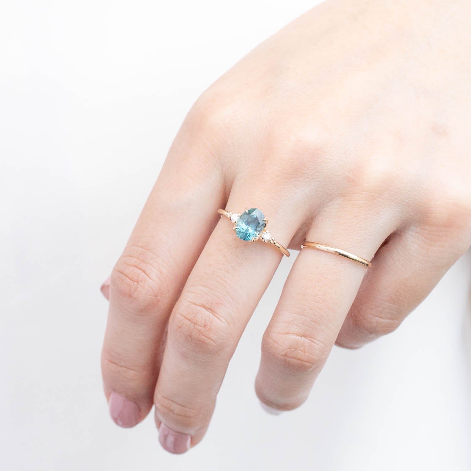 Hand wearing Estel Ring with 1.78ct light blue-green Montana sapphire set in 14k yellow gold band