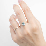 Hand wearing Nina Ring with 1.4ct light blue Montana sapphire set in 14k yellow gold tapered band