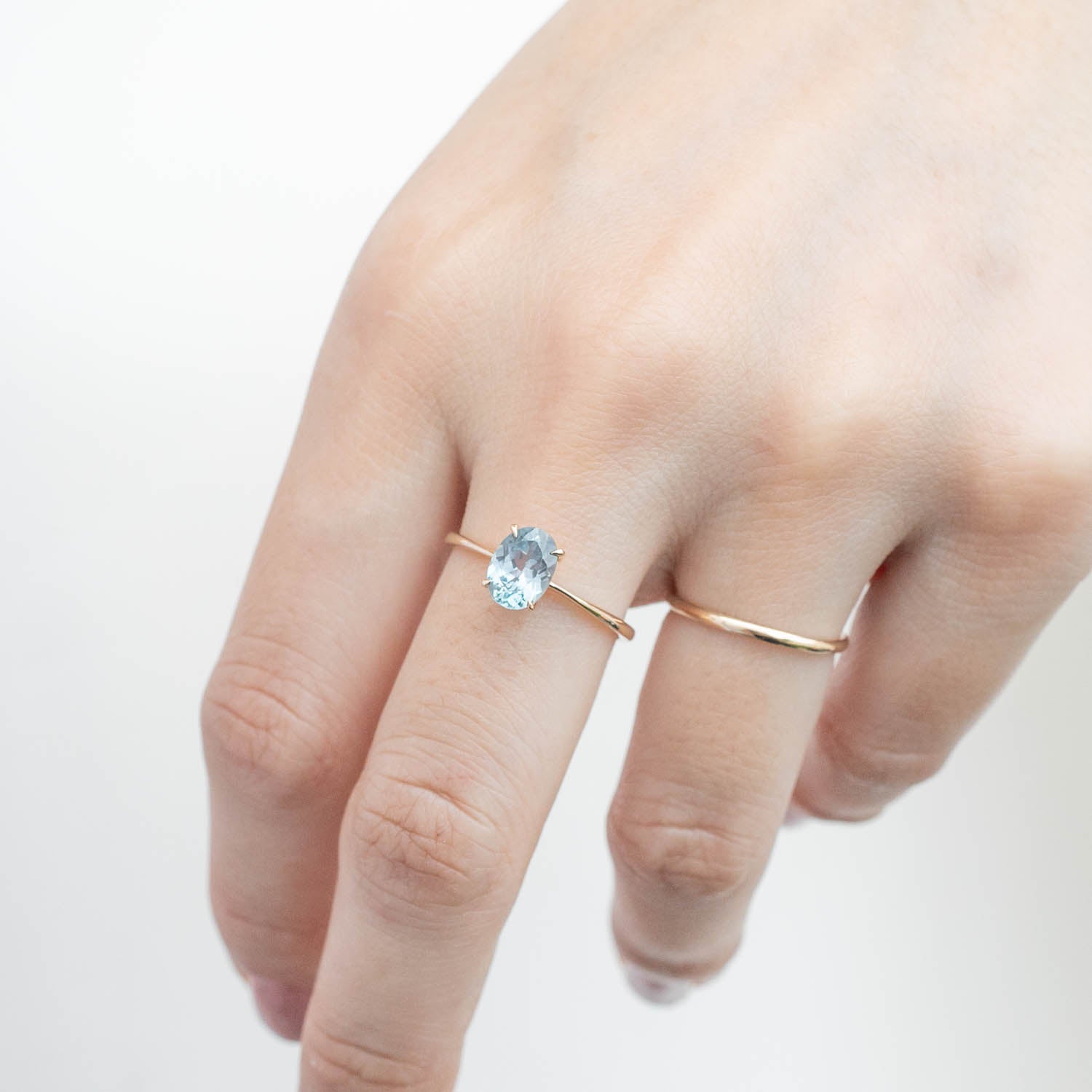 Hand wearing Nina Ring with 1.4ct light blue Montana sapphire set in 14k yellow gold with tapered band