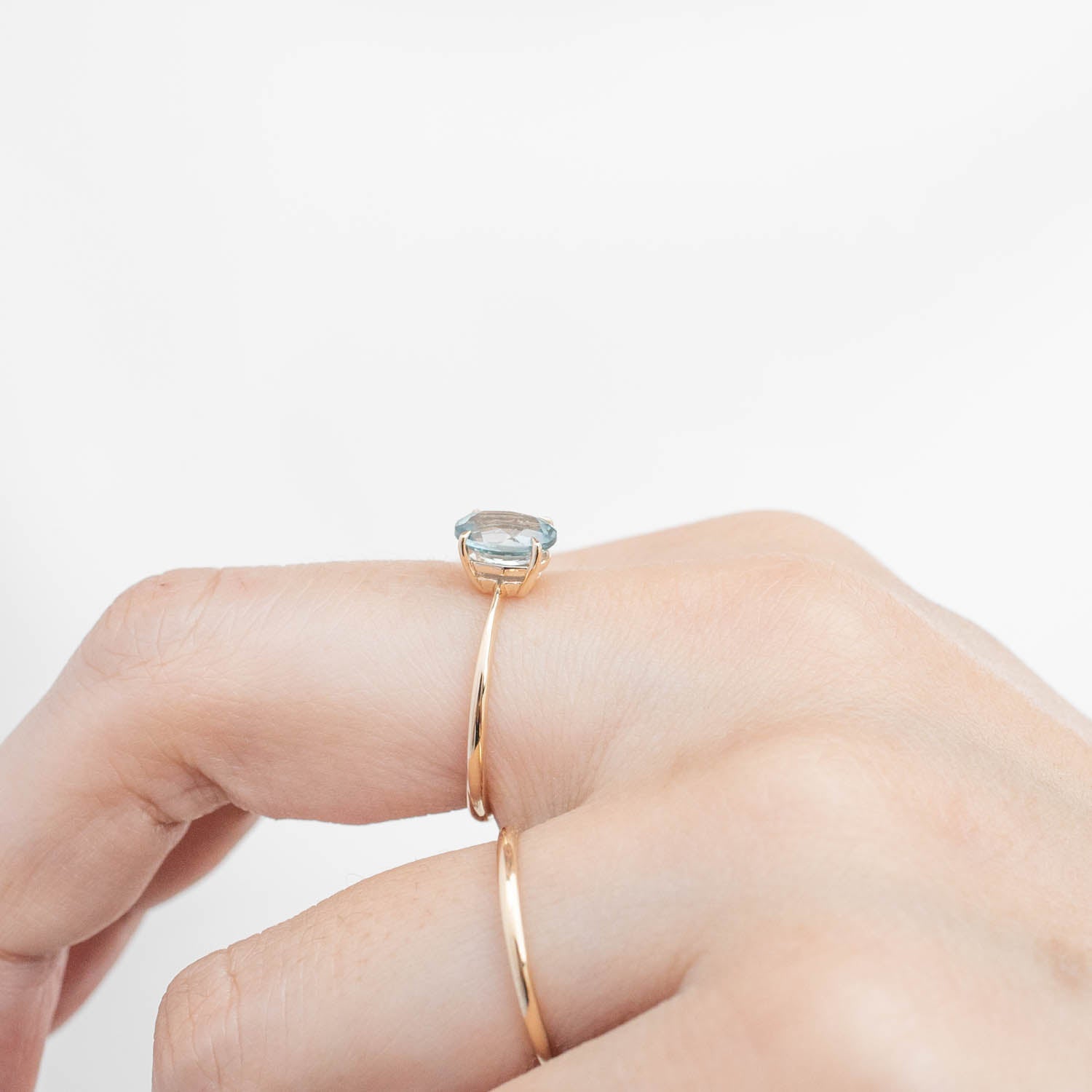 Close-up of a hand wearing a 14k yellow gold Nina Ring with a 1.4ct light blue Montana Sapphire gemstone