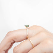 Hand wearing Maria Ring 1.53ct oval green Queensland sapphire in 14k yellow gold with diamond accents