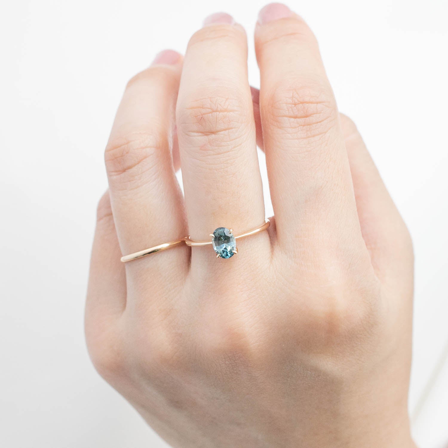 Close-up of hand wearing Nina Ring with 0.98ct green Montana sapphire set in 14k yellow gold band