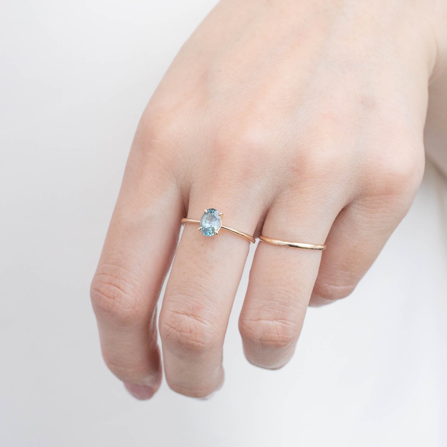Close-up of a hand wearing a one-of-a-kind Nina Ring with 0.98ct green Montana sapphire set in 14k yellow gold band