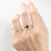 Close-up of hand wearing a 14k yellow gold ring with 0.85ct Queensland peacock sapphire and white accent diamonds