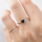 Hand wearing a 14k yellow gold ring with 0.85ct Queensland peacock sapphire and white accent diamonds